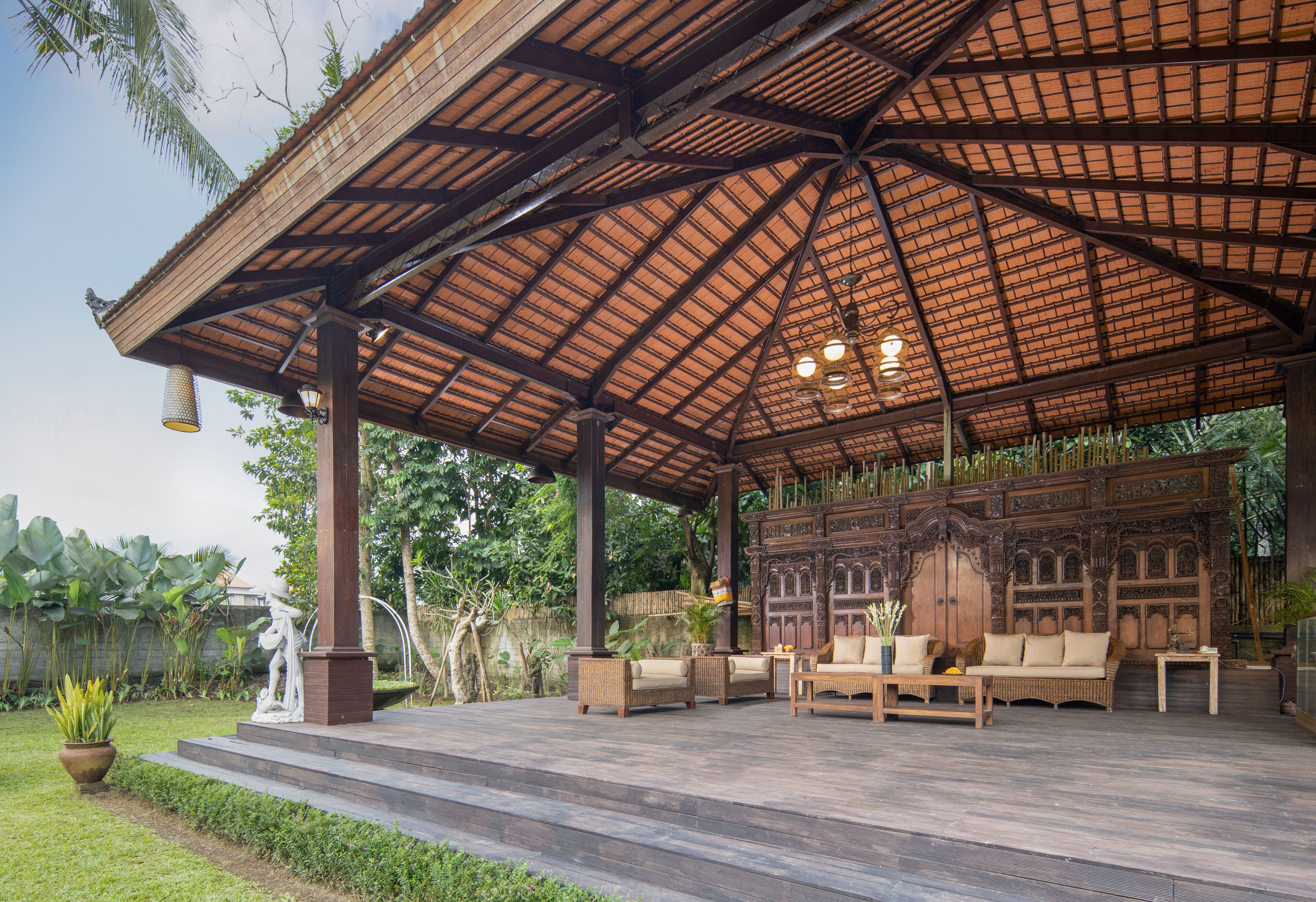 A covered outdoor seating area with wooden furniture and a decorative backdrop.