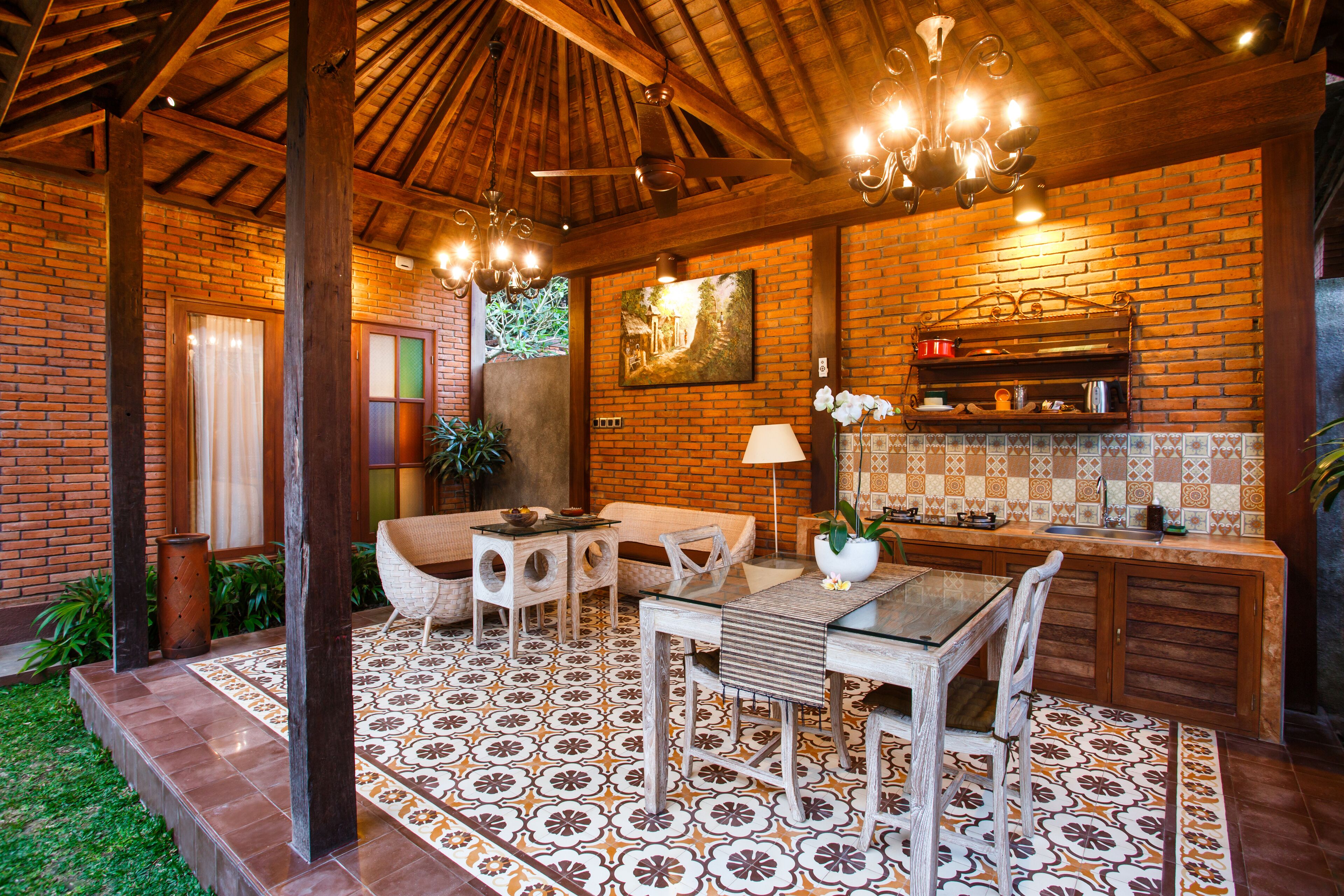 A rustic kitchen with a brick wall, wooden beams, and a tiled floor.