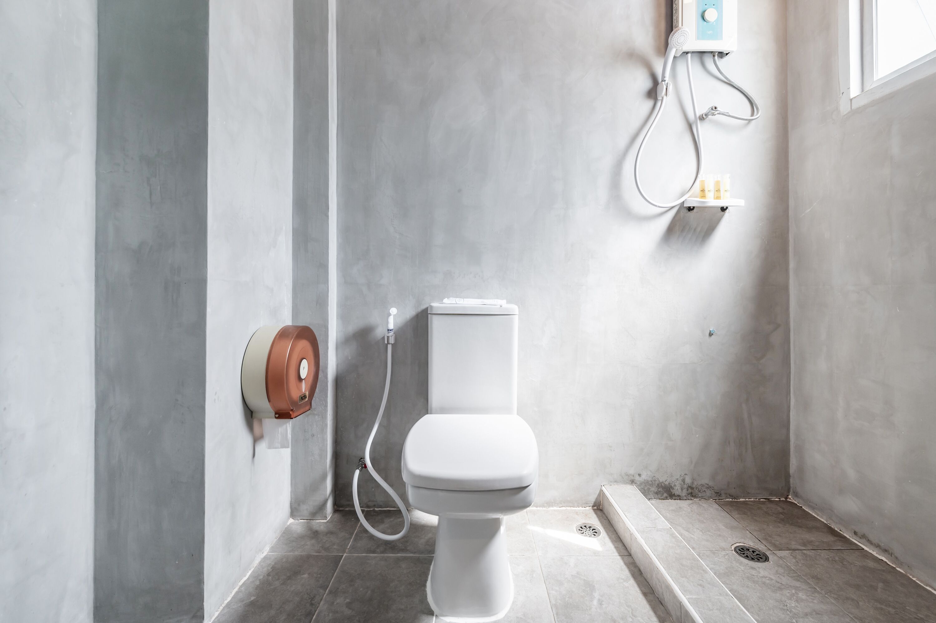 A modern bathroom with a toilet, a shower, and a hand dryer.