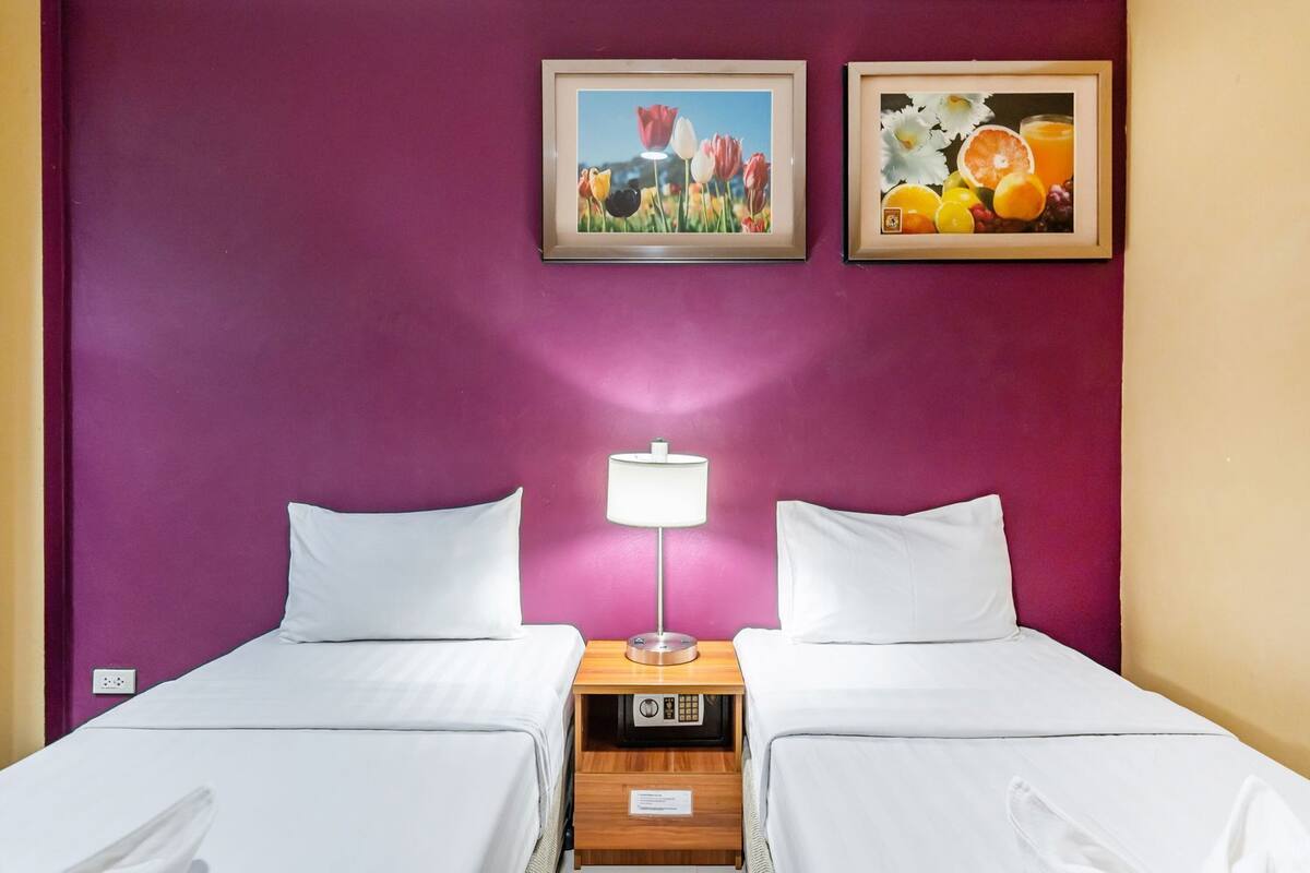 Une chambre d’hôtel avec deux lits, une table de chevet avec une lampe et deux tableaux encadrés au mur.