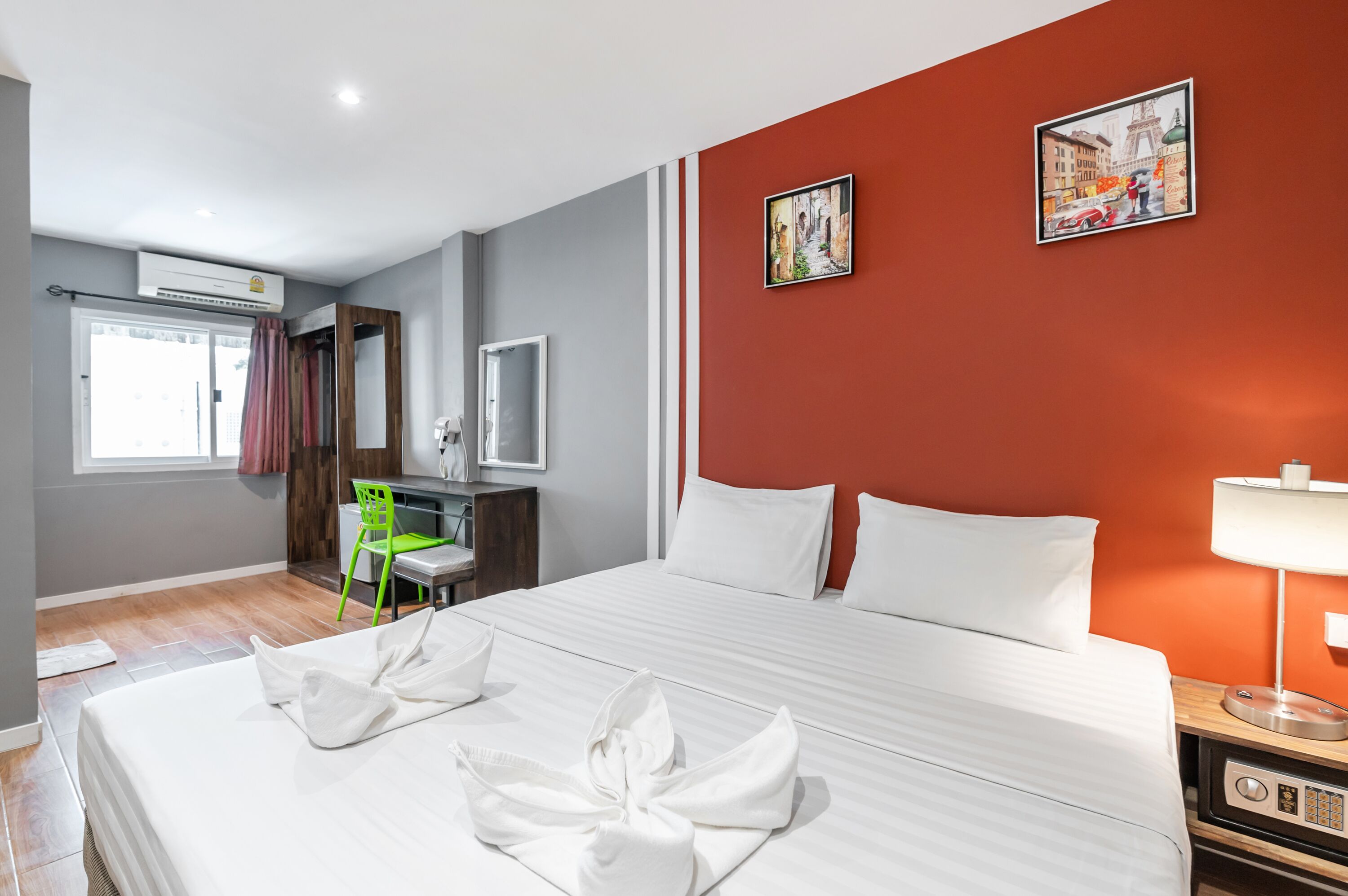 Een hotelkamer met een bed, een bureau, een stoel, een televisie en kunst aan de muur.
