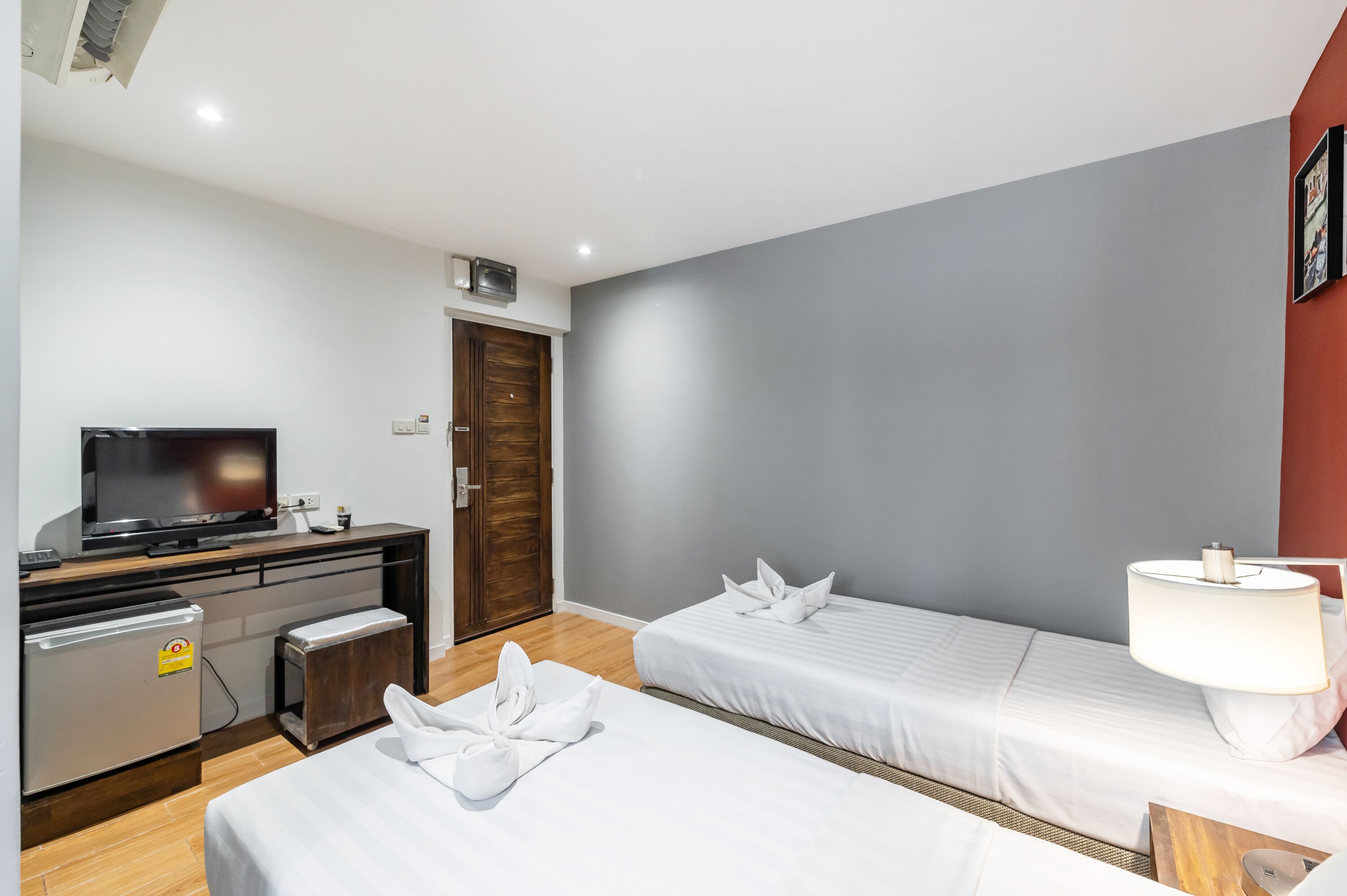A hotel room with two beds, a TV, a mini-fridge, and a lamp.