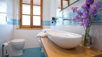 Ein Badezimmer mit Toilette, großem Waschbecken und Spiegel darüber.