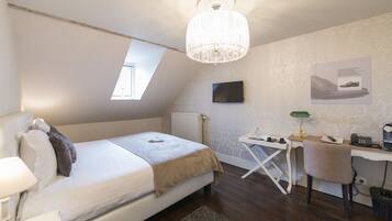 Een slaapkamer met een bed, bureau, stoel en een kroonluchter.