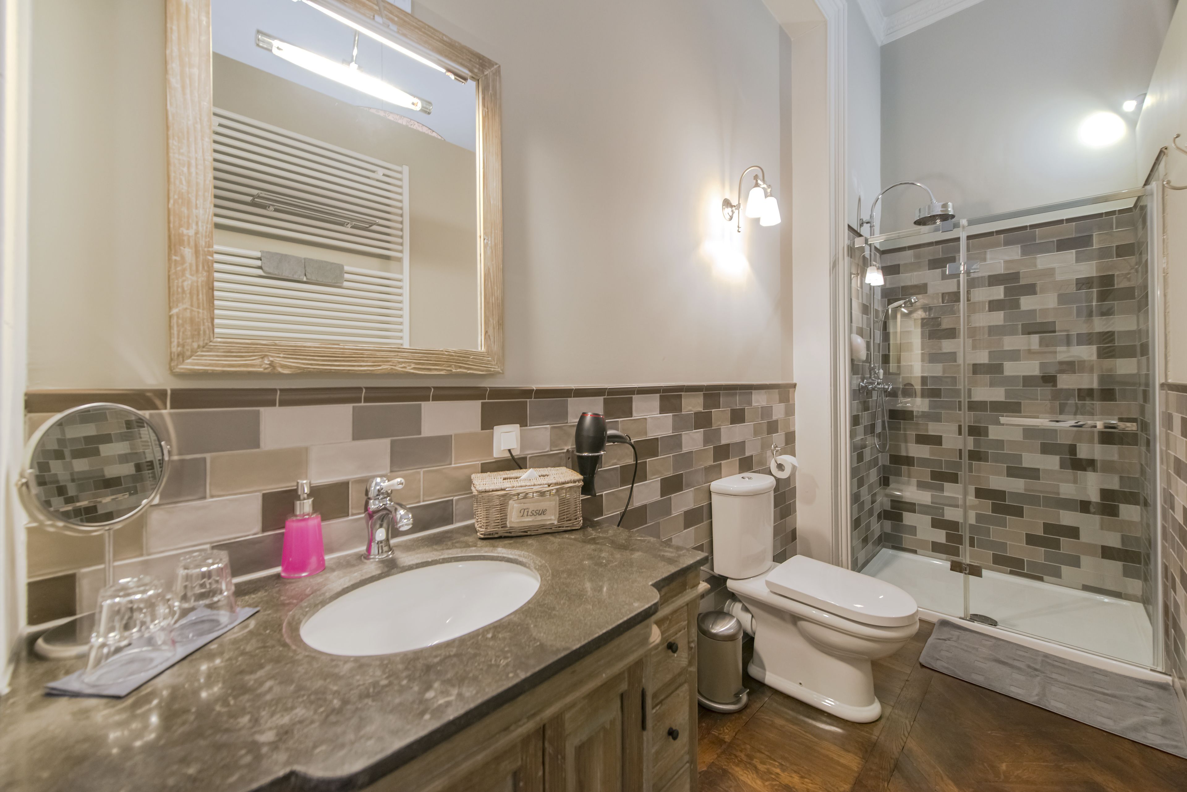 A bathroom with a sink, mirror, toilet, and shower.