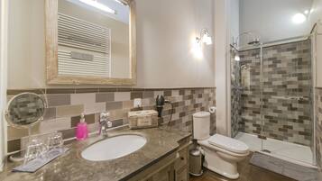A bathroom with a sink, mirror, toilet, and shower.