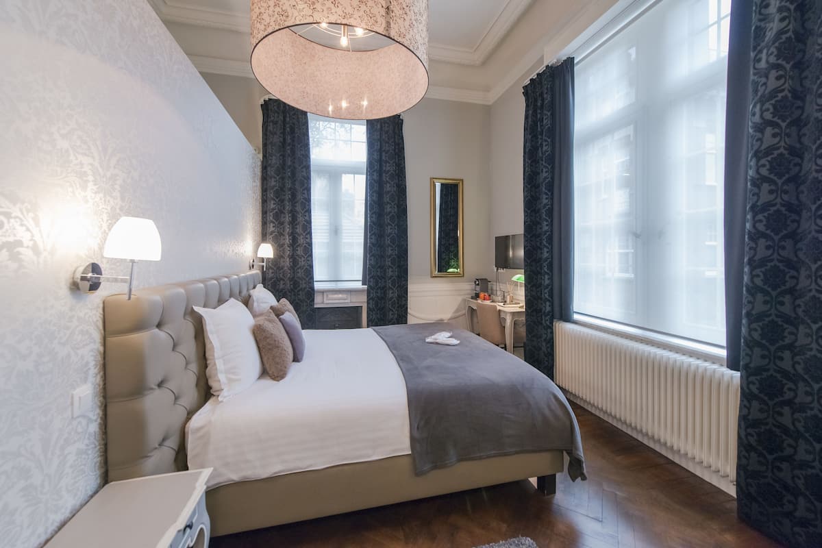 Une chambre spacieuse avec un grand lit, un bureau et un miroir.