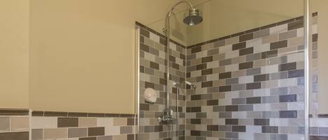 Un baño con inodoro, cabina de ducha y paredes de azulejos.
