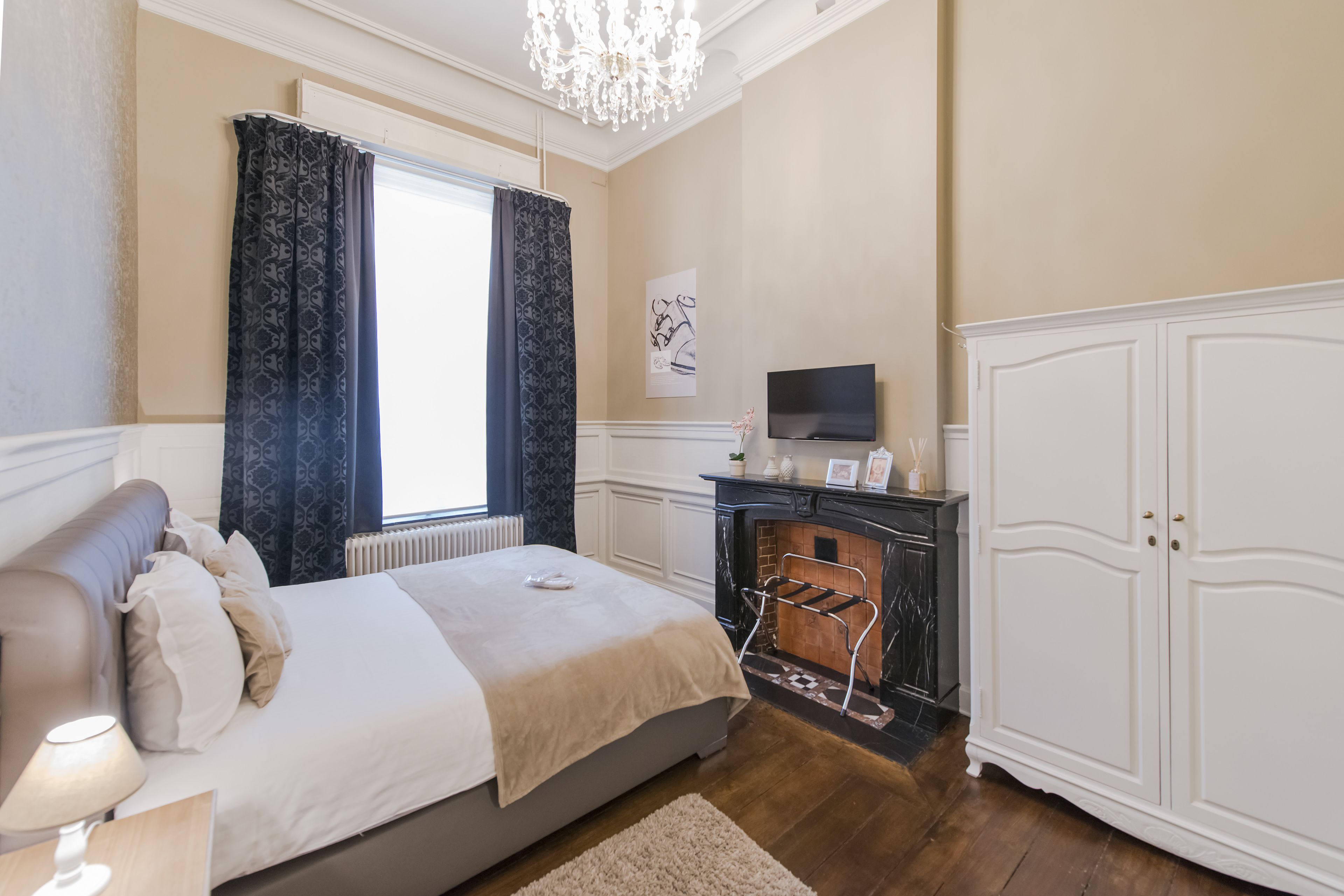 Une chambre à coucher comprenant un lit, une télévision, une cheminée et une armoire.