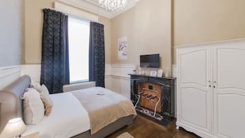 Une chambre à coucher comprenant un lit, une télévision, une cheminée et une armoire.