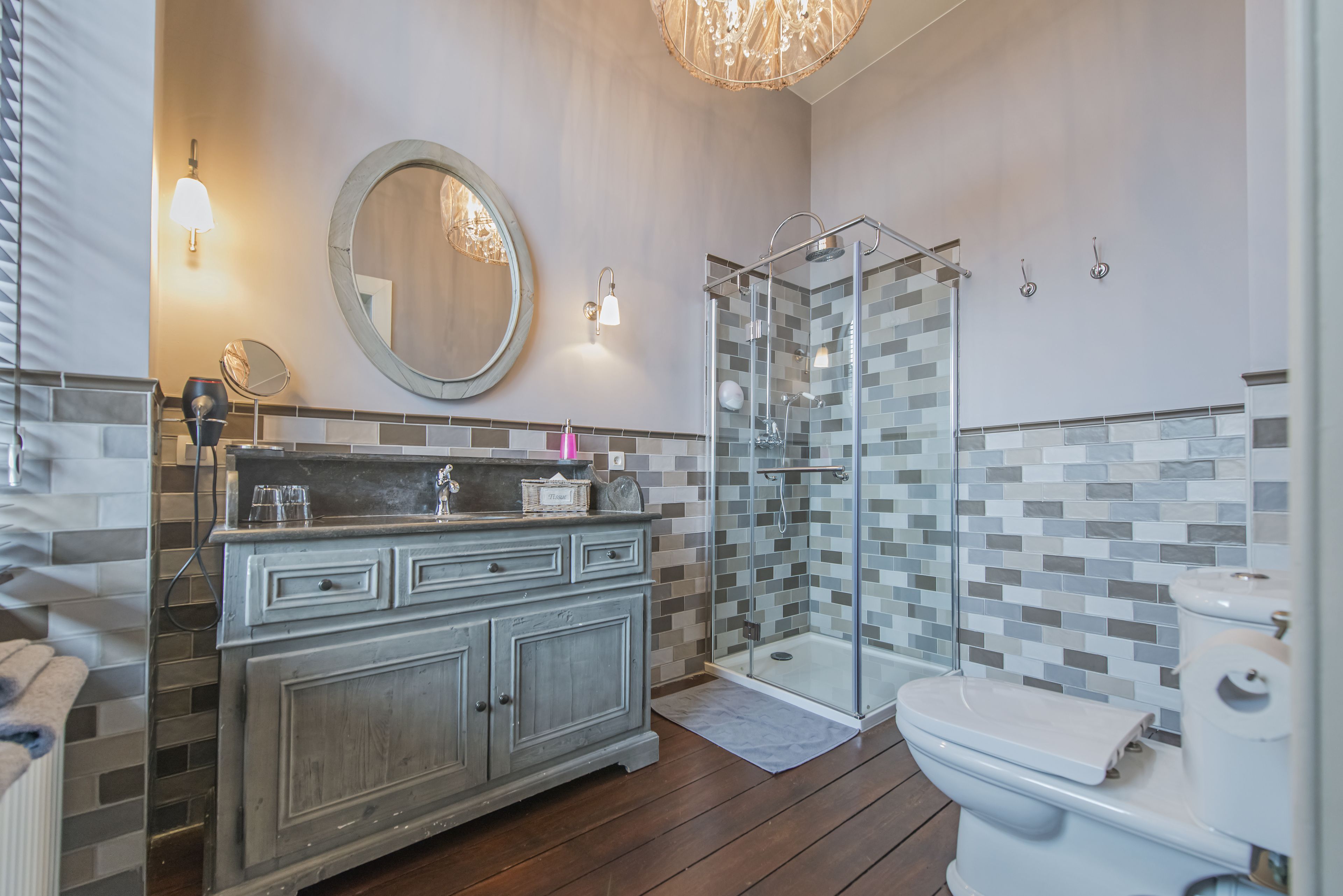 Ein Badezimmer mit einem Holzbadezimmer-Möbel, einer Duschkabine aus Glas, einer Toilette und einem großen Spiegel.