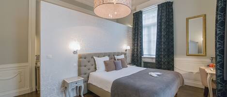 A bedroom with a large bed, bedside tables, a dresser, a mirror, and a window with curtains.