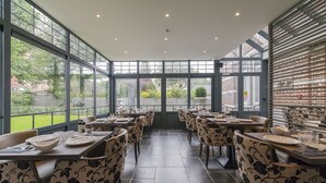 A restaurant with large windows, tiled floor, and patterned chairs. - 't Huys van Steyns (Tongeren)