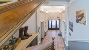 A grand hallway with a wooden staircase, a chandelier, and a patterned carpet. - 't Huys van Steyns (Tongeren)
