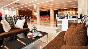 A modern hotel lobby with a seating area, a reception desk, and a dining area. - Metro Resort Pratunam (Bangkok)