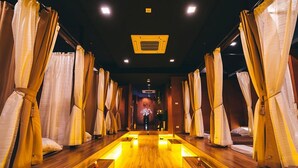 A spa room with wooden flooring, multiple beds with curtains, and a central light fixture. - Metro Resort Pratunam (Bangkok)