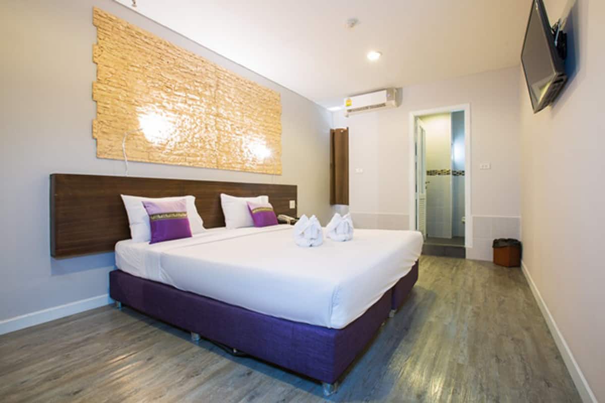 A modern hotel room with a large bed, a wooden headboard, and a textured wall decoration.