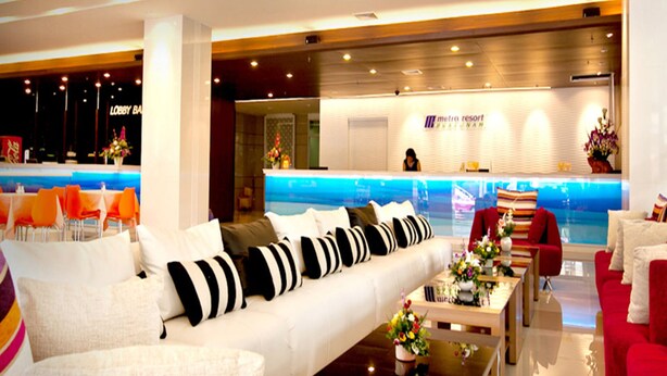 A hotel lobby with a reception desk, a pool area, and seating arrangements. - Metro Resort Pratunam (Bangkok)