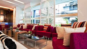 A modern hotel lobby with red sofas, a glass coffee table, and a reception area. - Metro Resort Pratunam (Bangkok)