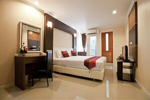 A hotel room with a bed, desk, chair, and a television. - Metro Resort Pratunam (Bangkok)