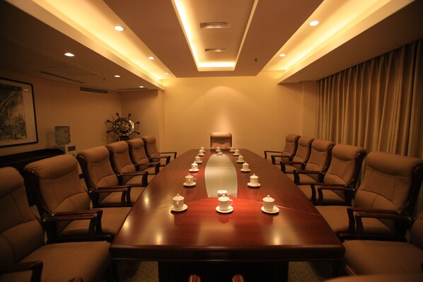 A conference room with a long table, multiple chairs, and a ship's wheel decoration on the wall.