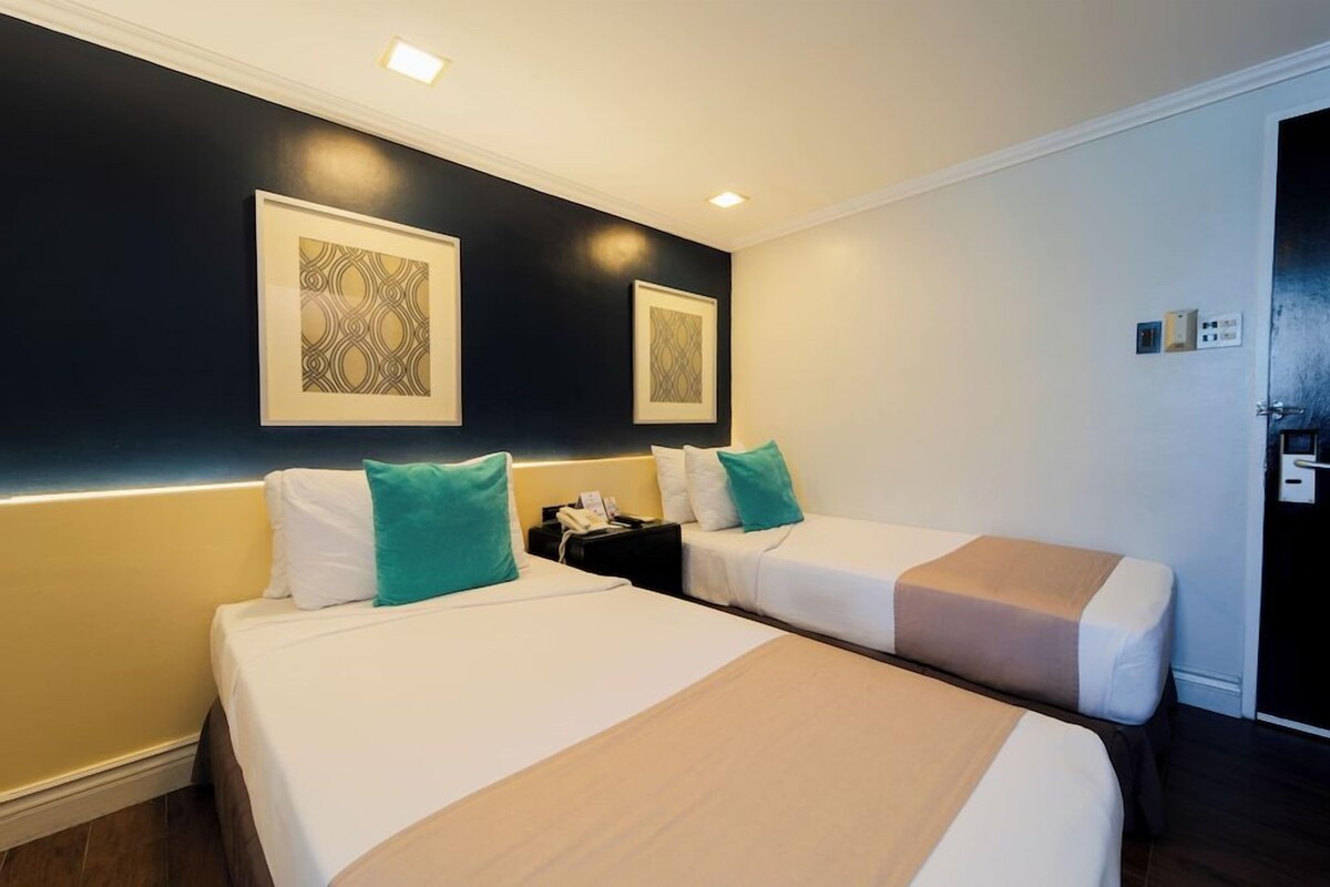 A hotel room with two beds, a nightstand, and a wall-mounted telephone.