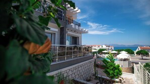 A modern multi-story building with balconies, a swimming pool, and a view of the sea. - Twins Hotel (Cesme)