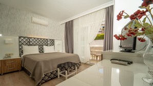 A modern hotel room with a large bed, bedside table, and a TV on a stand. - Twins Hotel (Cesme)
