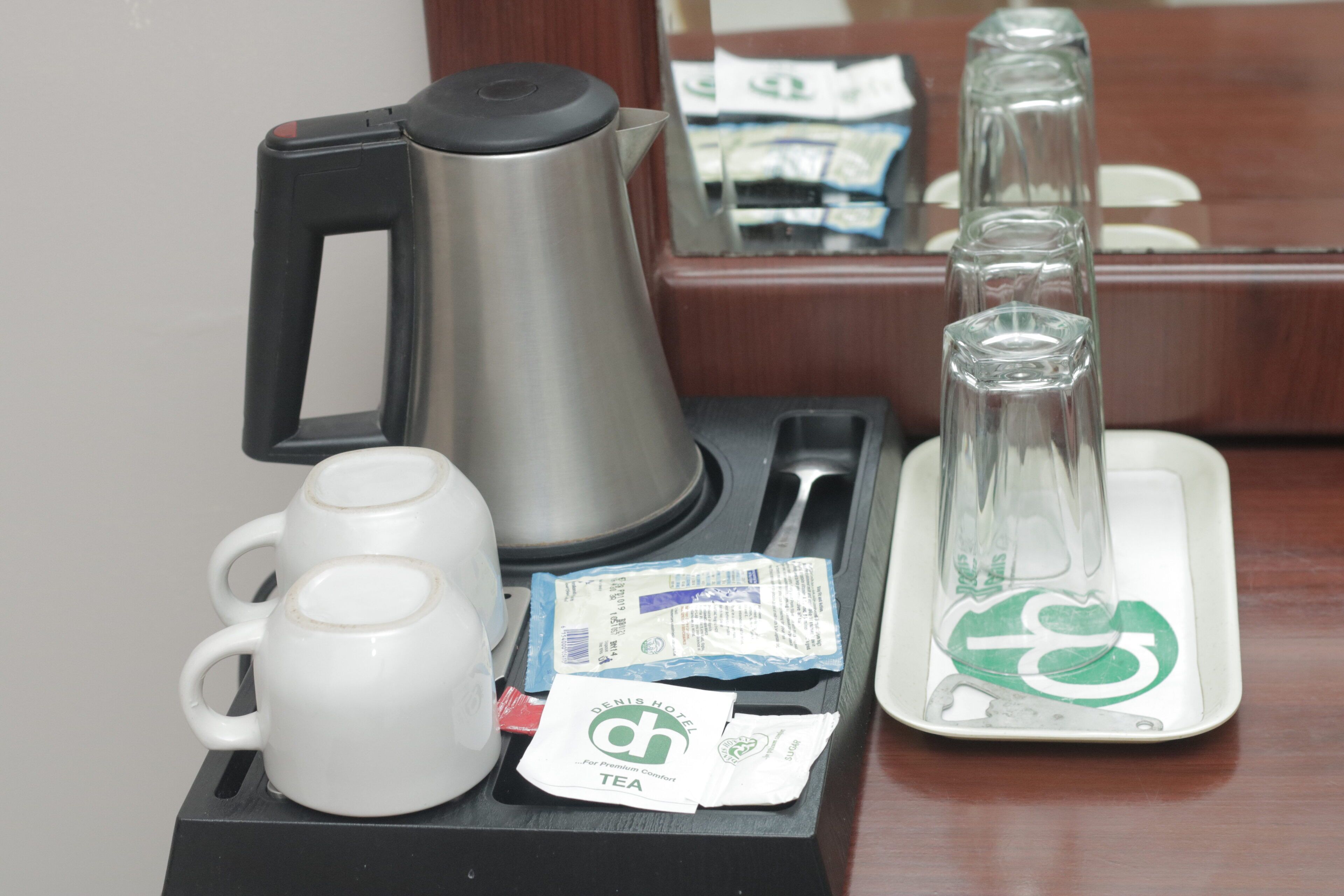 A coffee maker, a mug, tea packets, and a glass carafe on a tray.