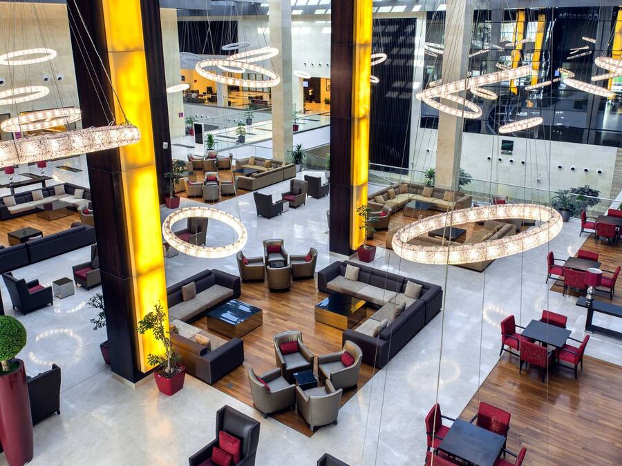 Un hall amplio con varias zonas de estar, grandes lámparas circulares y un diseño arquitectónico moderno.