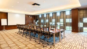 A conference room with a long table, chairs, a projector, and large windows.
