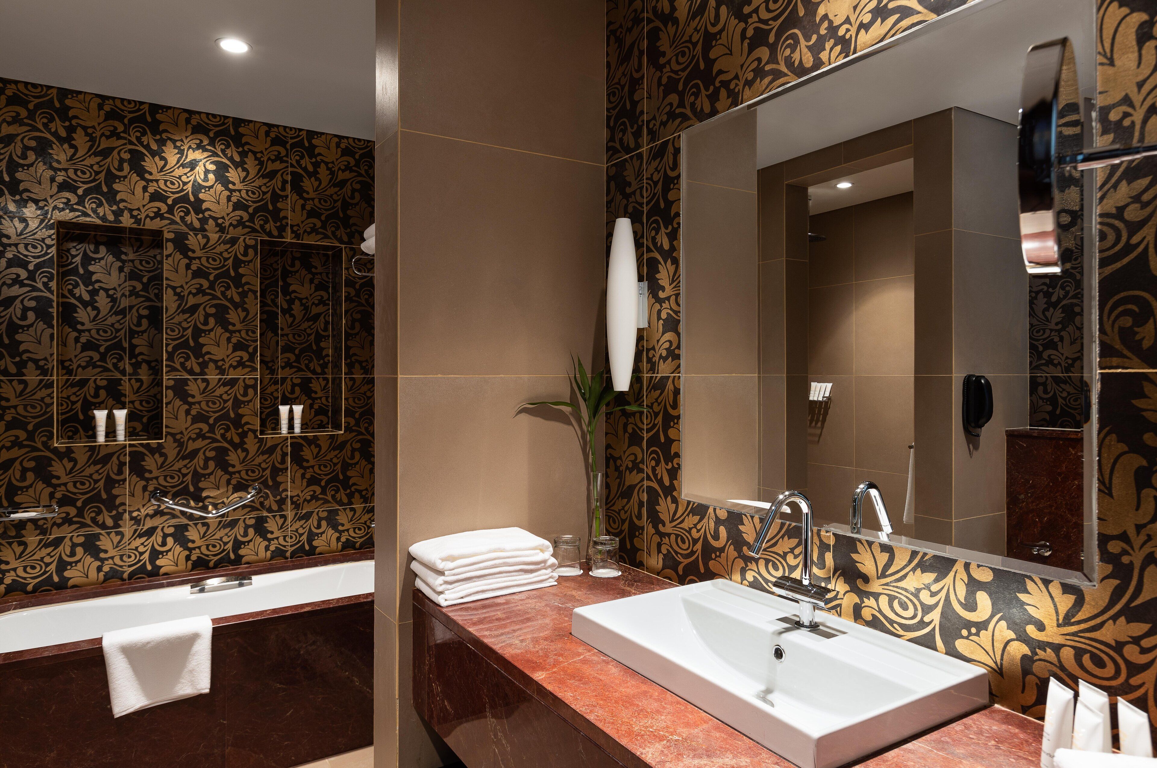 A bathroom with a large mirror, a bathtub, and a sink.