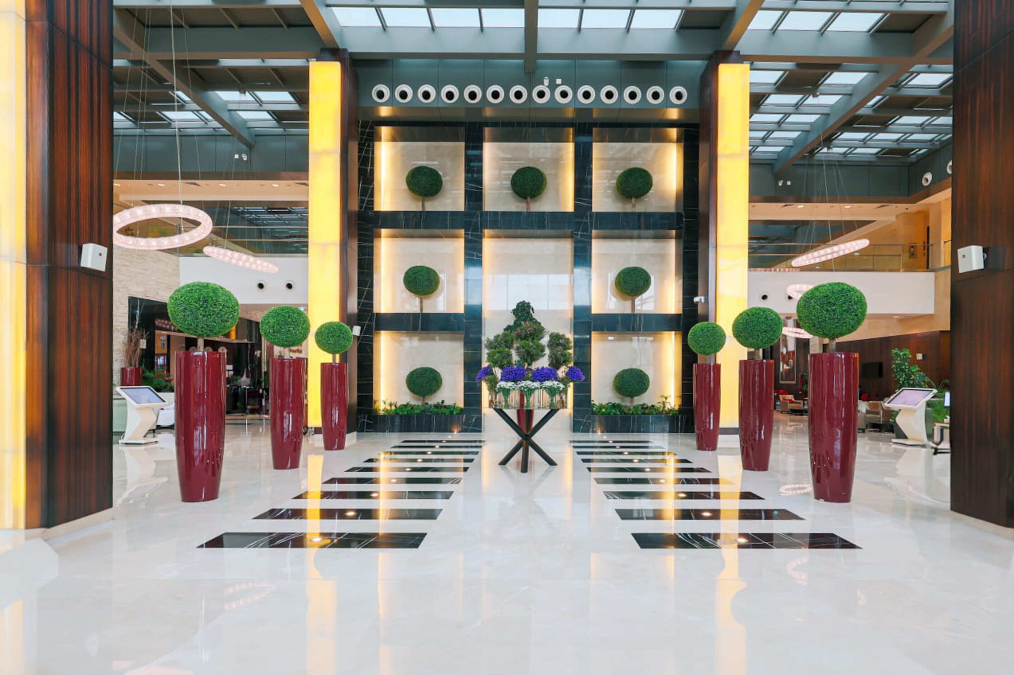 A modern lobby with a central floral arrangement, large decorative columns, and a checkered floor pattern.