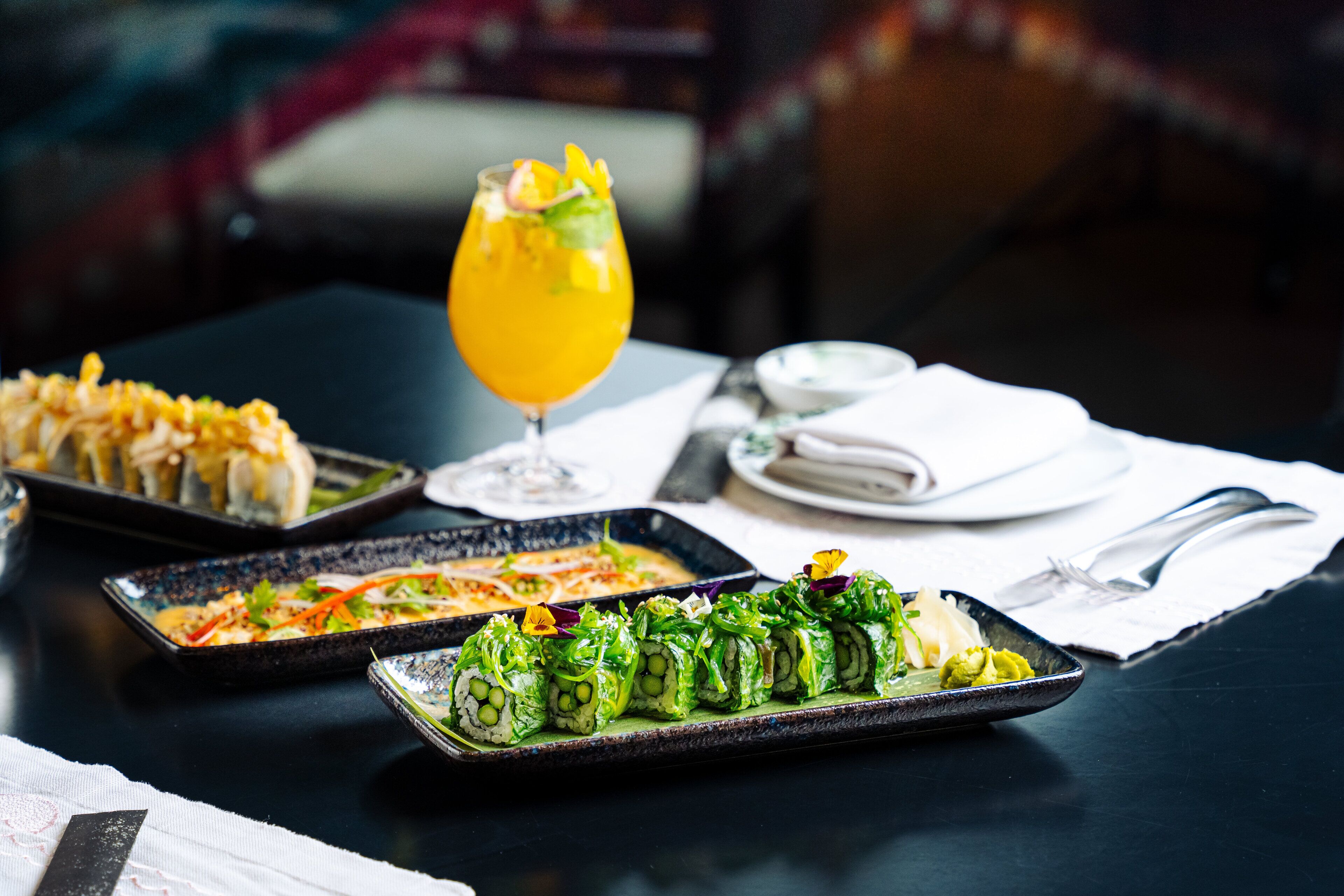 A table with various dishes, including sushi and a glass of orange juice.