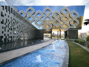 Un edificio moderno con fachada geométrica y una fuente en primer plano.