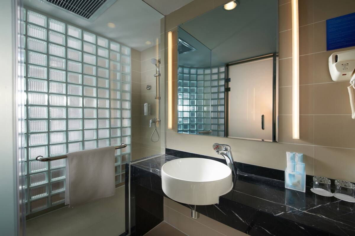 A modern bathroom with a glass shower enclosure, a white sink, and a large mirror.