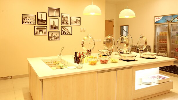Ein Hotel-Empfangsbereich mit einer Rezeption, gerahmten Bildern an der Wand und einem Getränkeautomaten.
