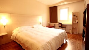 Ein Hotelzimmer mit einem großen Bett, Nachttischen, einem Schreibtisch, einem Stuhl und einem Fenster.