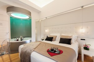 A modern bedroom with a large bed, a built-in bathtub, and a mirror.