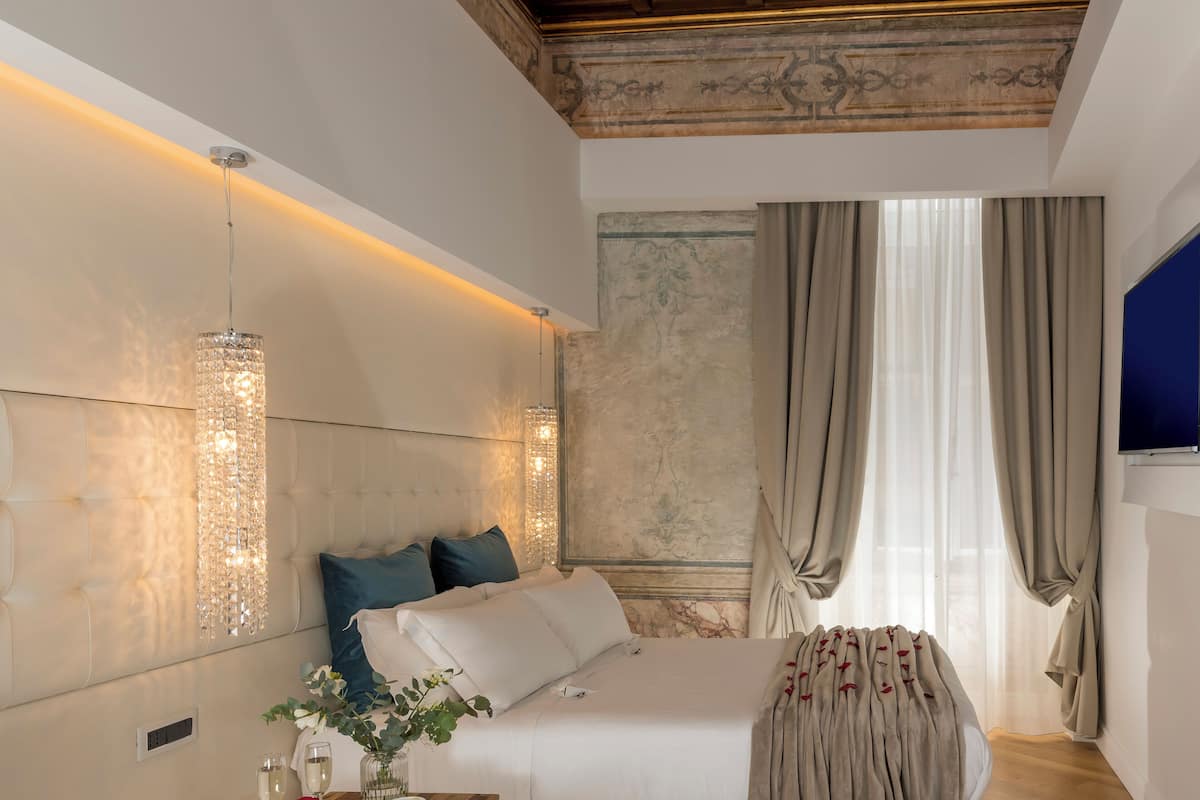 A modern bedroom with a large bed, a chandelier, and a view of the outdoors.