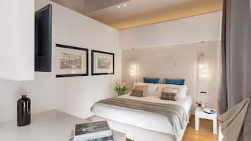 Un dormitorio moderno con una cama grande, mesitas de noche, cuadros enmarcados y una pequeña mesa con un florero.