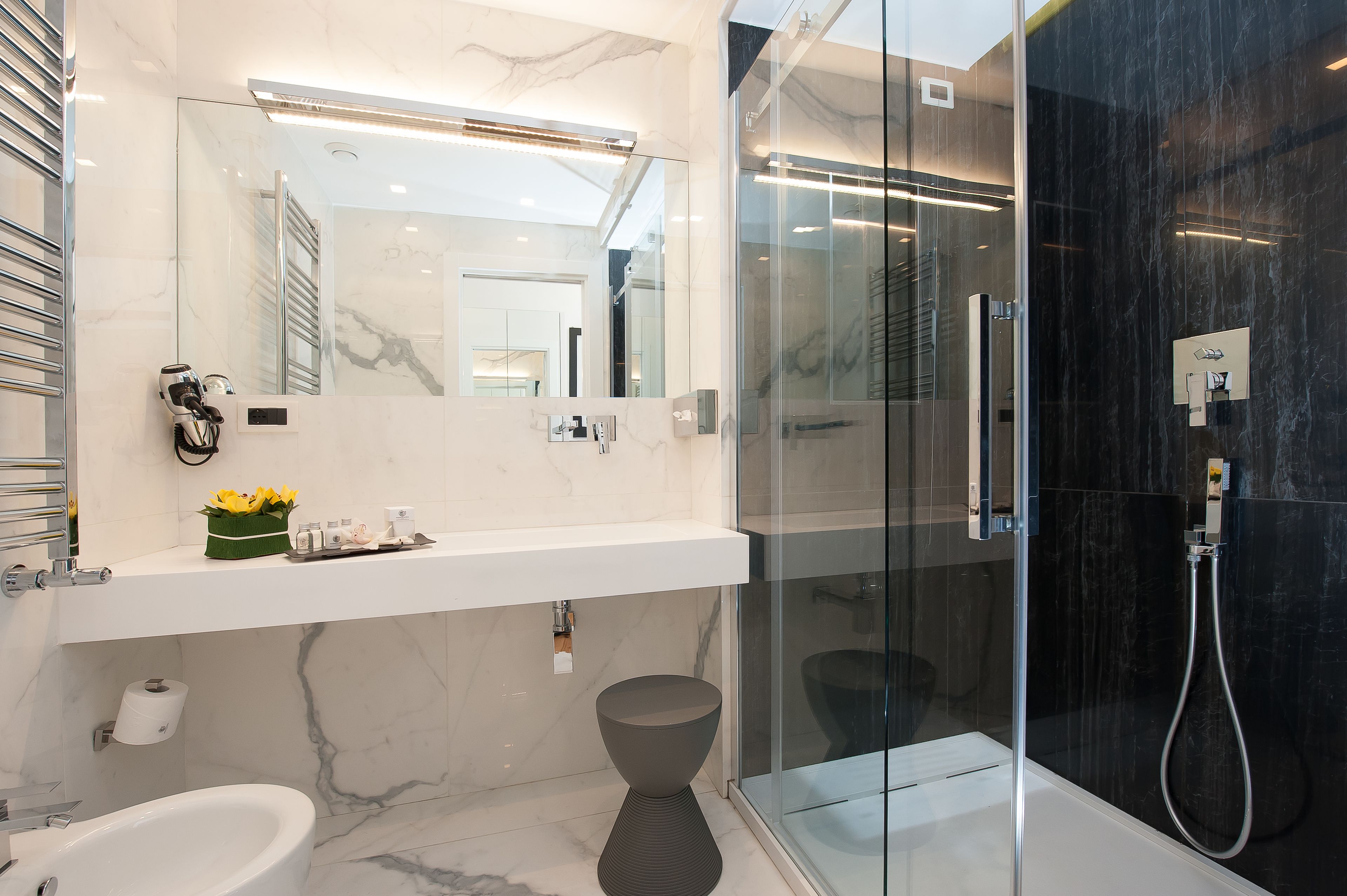Une salle de bain moderne avec un meuble-lavabo en marbre, une douche à parois de verre et un bidet.