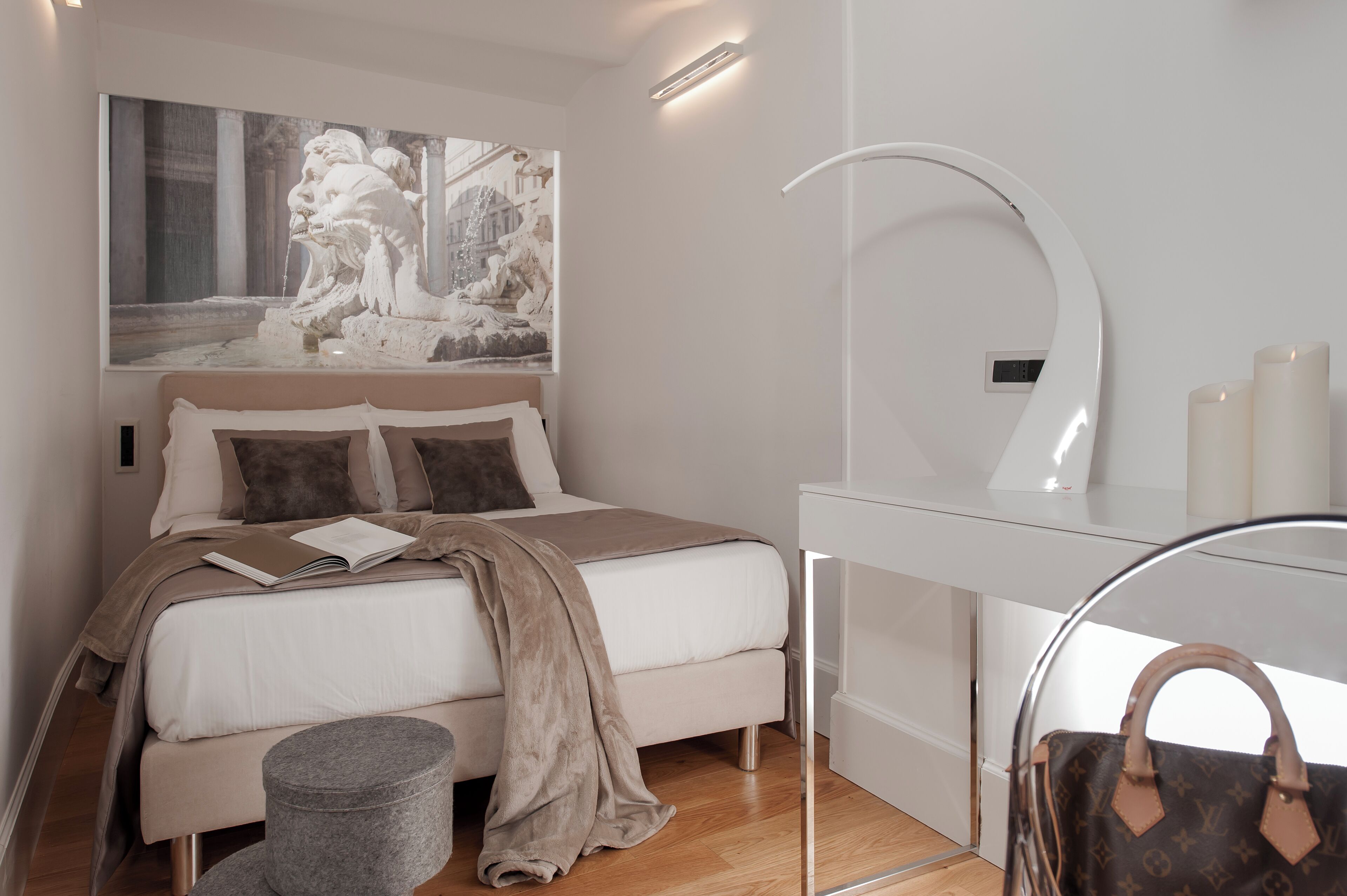 A modern bedroom with a bed, a bedside table, a mirror, and a wall-mounted artwork.