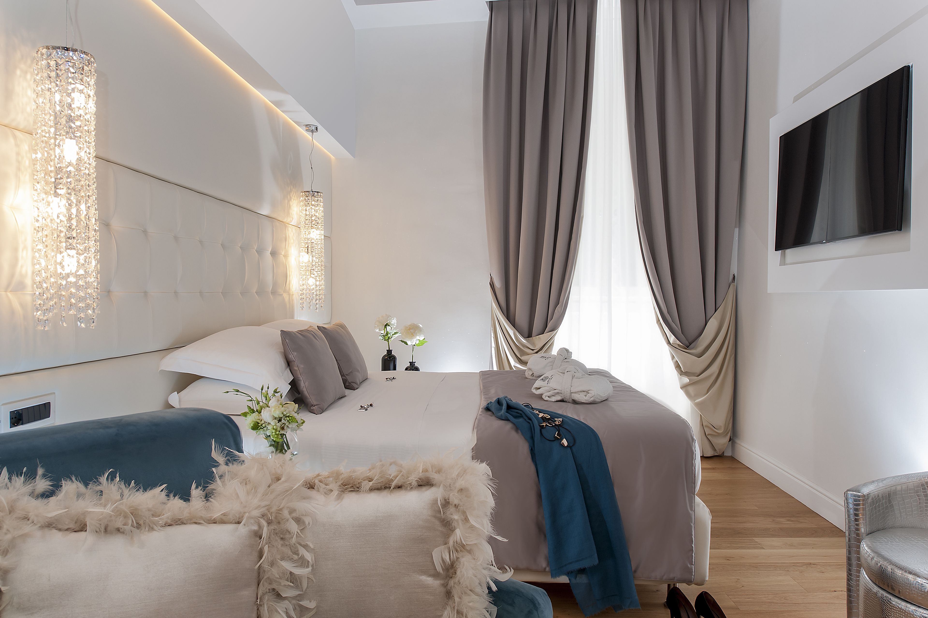 Ein modernes Schlafzimmer mit einem großen Bett, einem Fernseher und einem Kronleuchter.
