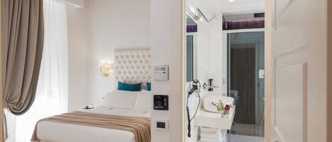 A modern bedroom with a large bed, a bedside table, a built-in headboard, and a bathroom with a sink and mirror.
