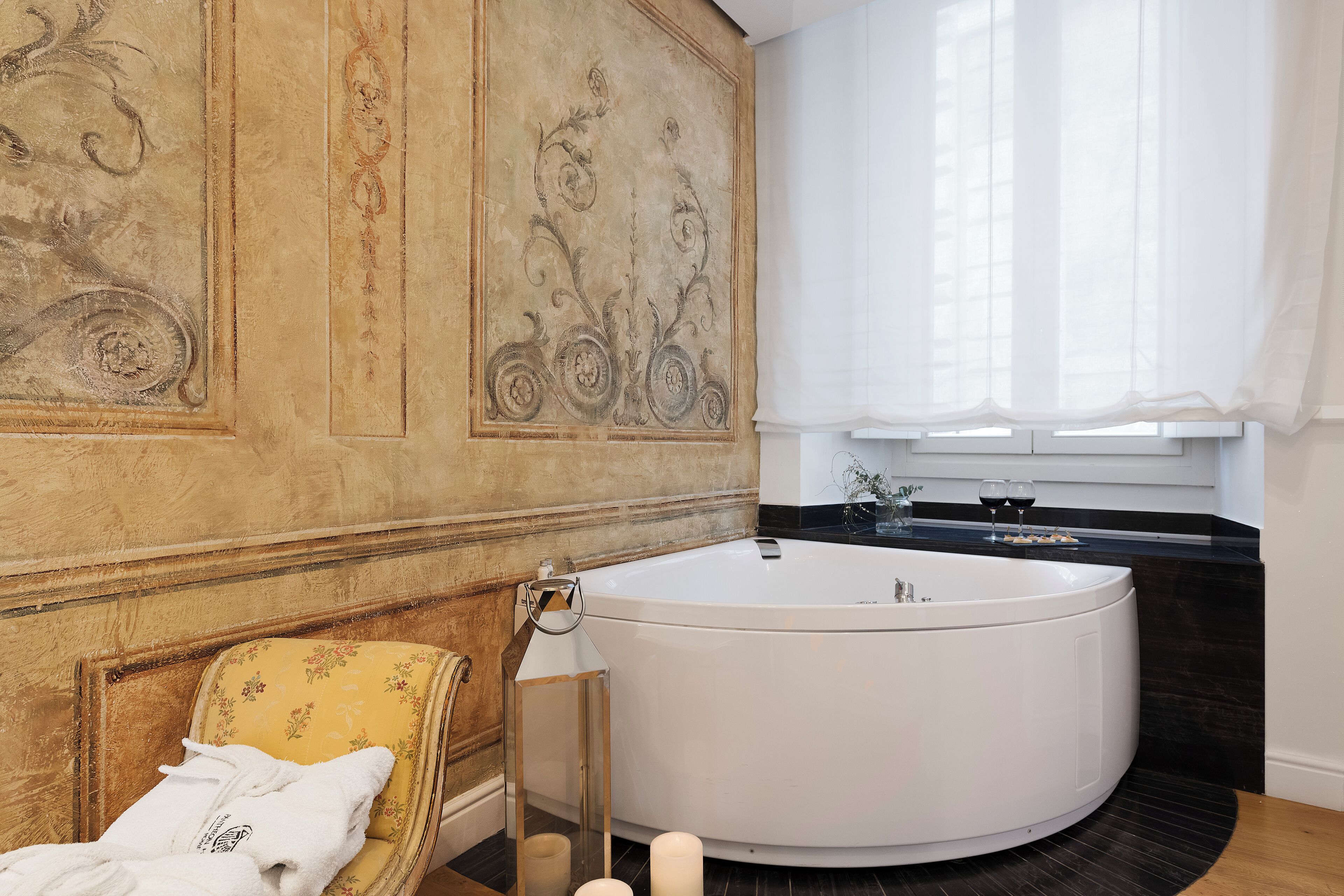 Ein Badezimmer mit einer großen Badewanne, einem Holzstuhl und einer Dekoration an der Wand.