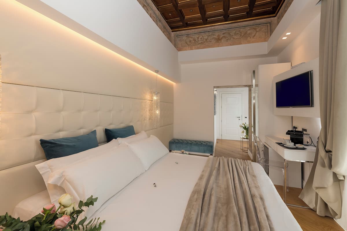 A modern bedroom with a large bed, a desk, and a TV.