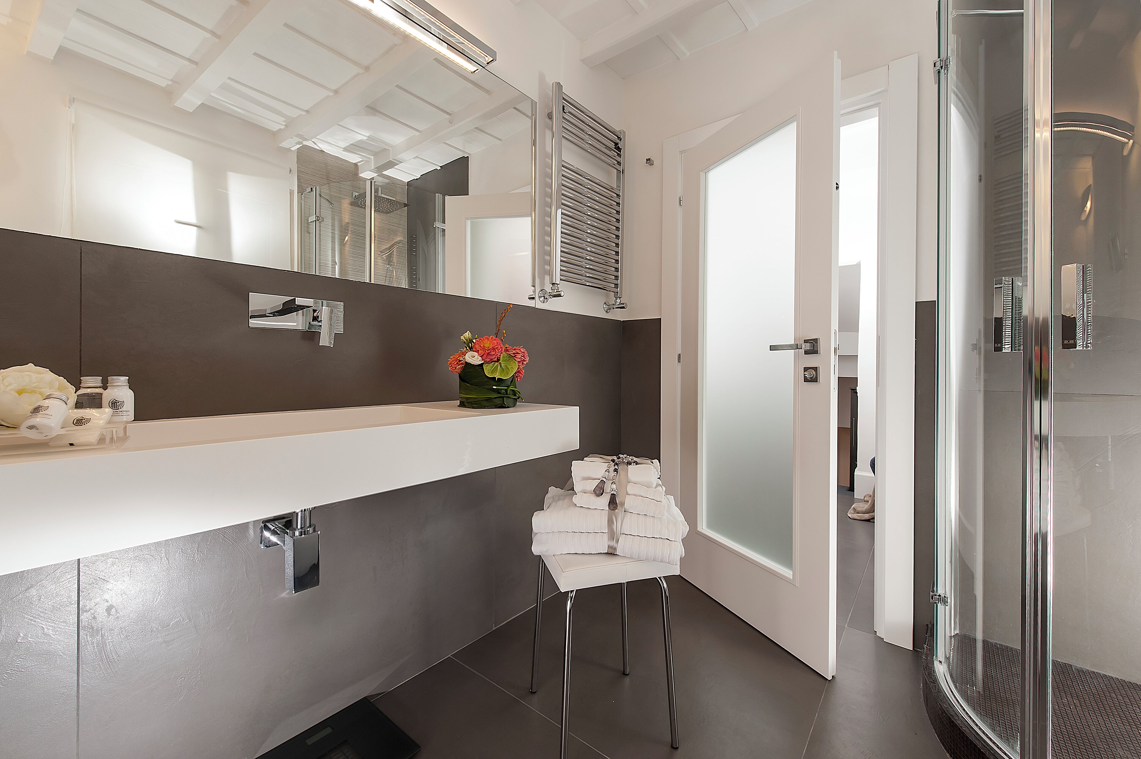Un baño moderno con un espejo grande, un perchero para toallas y una zona de ducha.