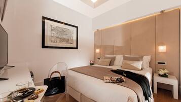 A modern hotel room with a large bed, a flat-screen TV, a clear glass chair, and a tray with pastries.