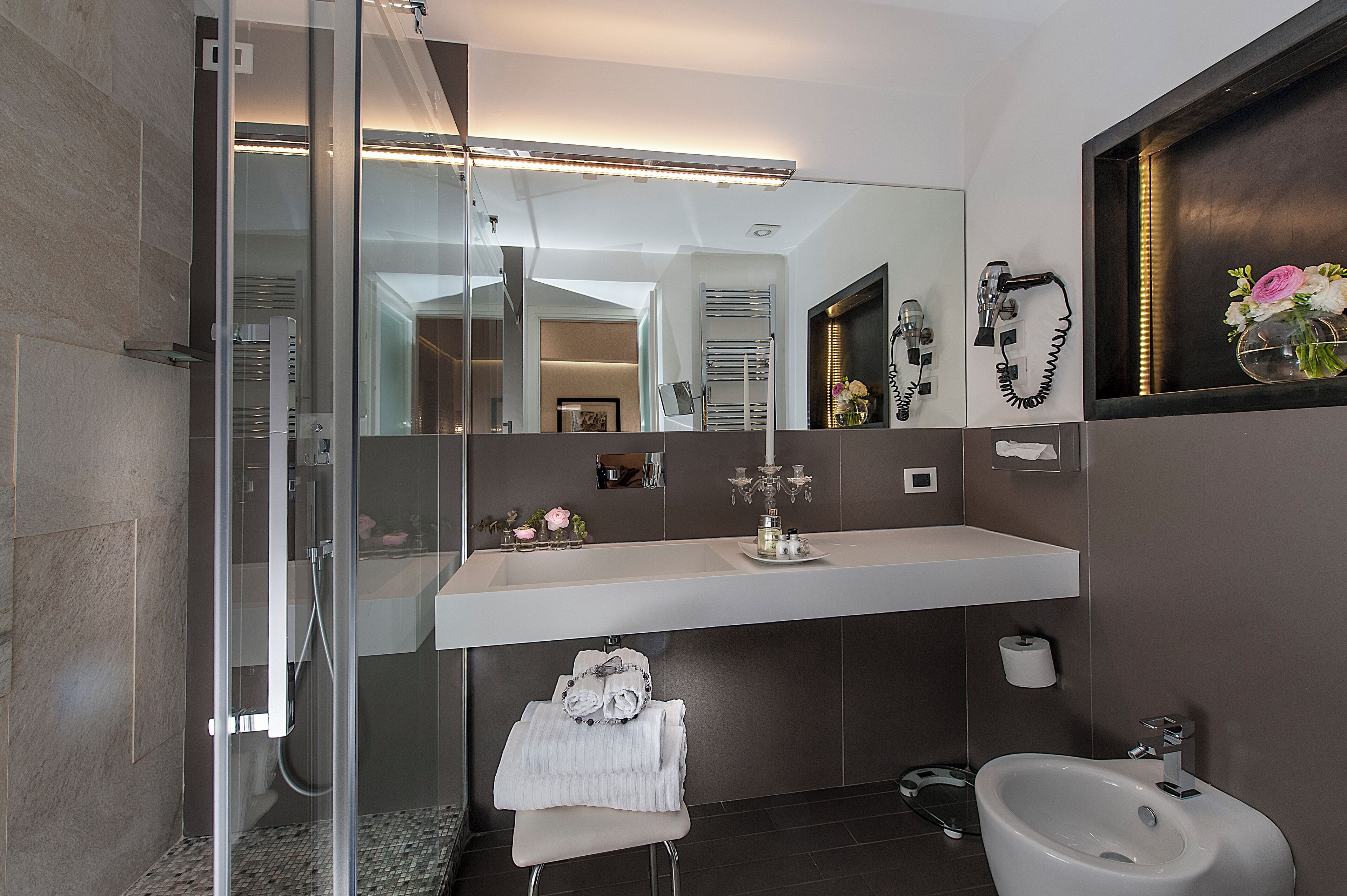 Een moderne badkamer met een douche met glazen wand, een grote spiegel en een wastafelmeubel met wastafel.
